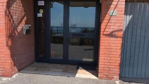 Une entrée d’immeuble avec une porte vitrée, une boîte aux lettres et une plaque portant le numéro « 72 ».