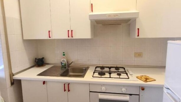 Une cuisine avec des meubles blancs, une cuisinière à gaz, un évier et un four à micro-ondes.