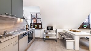 A compact kitchen with modern appliances, a dining area with a bench, and a window with a view. - Apartment 'Weitblick' (Top Floor Center) with Free Wi-Fi (max. 6 guests) (Pottenstein)