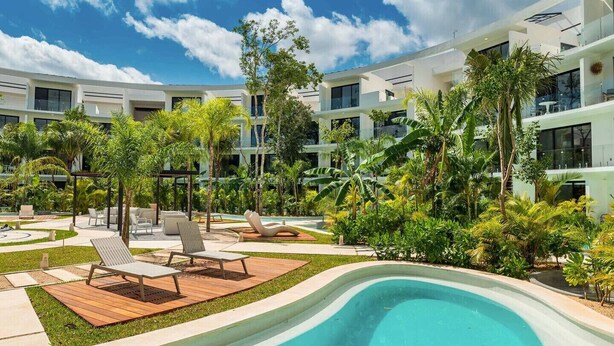 A modern hotel with a swimming pool, lounge chairs, and tropical landscaping. - Studio with King Bed in La Veleta (Tulum)