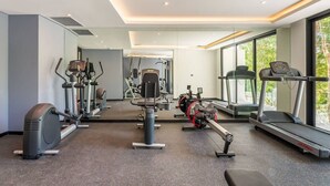 A modern gym with cardio machines, weight training equipment, and a large window providing natural light. - Studio with King Bed in La Veleta (Tulum)