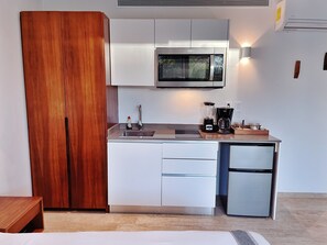 A compact kitchenette with a microwave, a coffee maker, and a refrigerator.