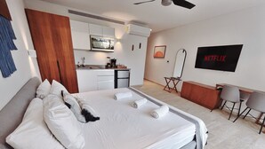 Une chambre d’hôtel moderne dotée d’un grand lit, d’une kitchenette, d’un téléviseur à écran plat et d’un coin salon.