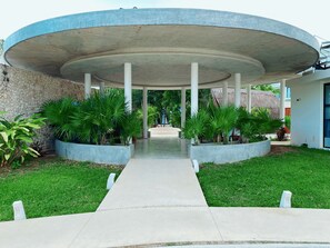 A modern building with a circular central structure, surrounded by a paved walkway and green landscaping.