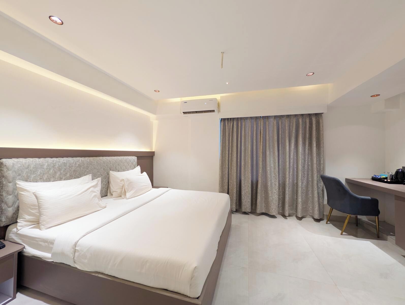 Una habitación de hotel moderna con una cama grande, un escritorio y una silla.