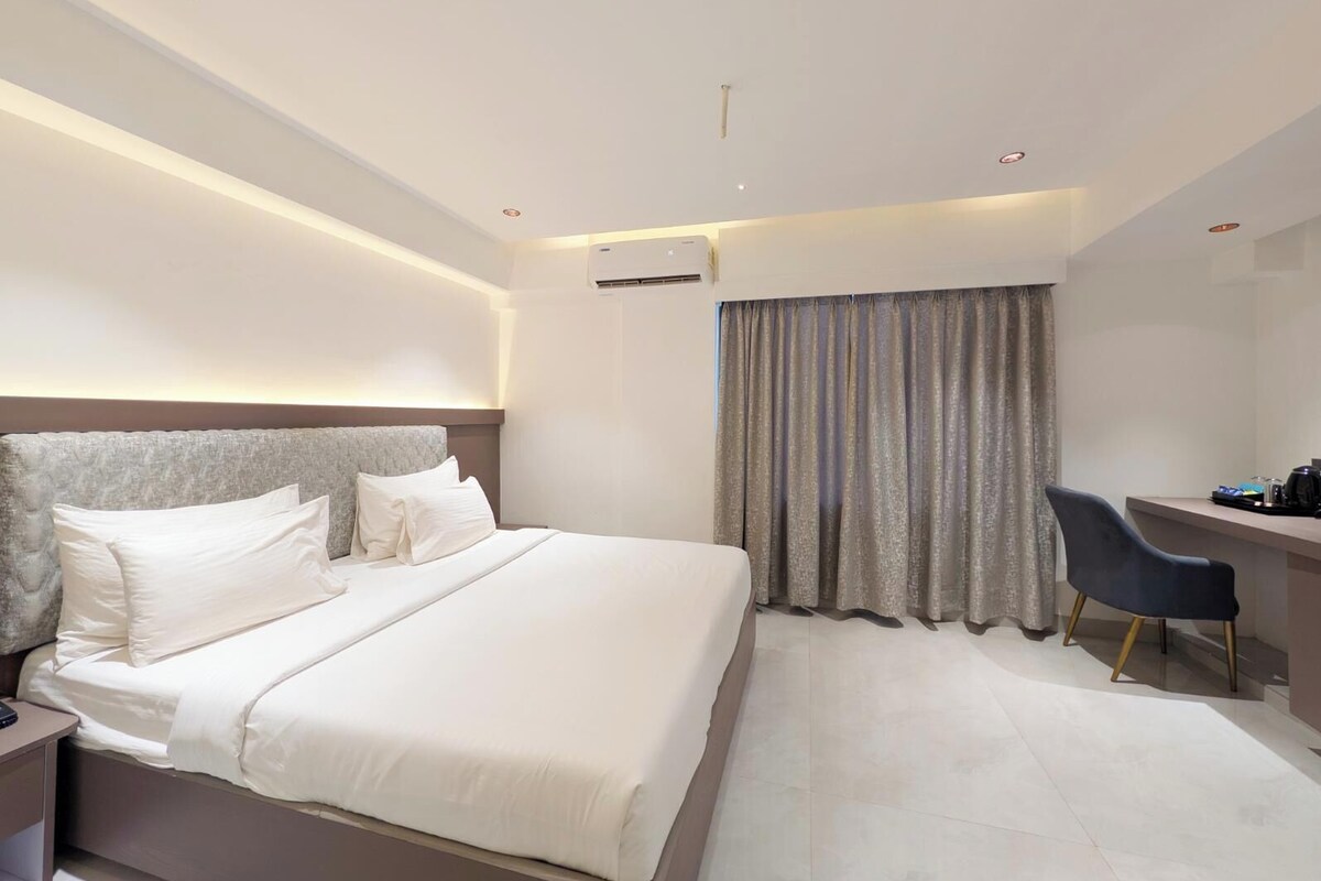 A modern hotel room with a large bed, a desk, and a chair.