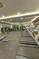 Une salle de sport équipée de tapis de course, d’appareils de musculation et d’un mur recouvert de miroirs.