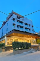 Un hôtel à plusieurs étages, doté d’un design moderne, avec une entrée imposante, une façade bien éclairée et une enseigne.