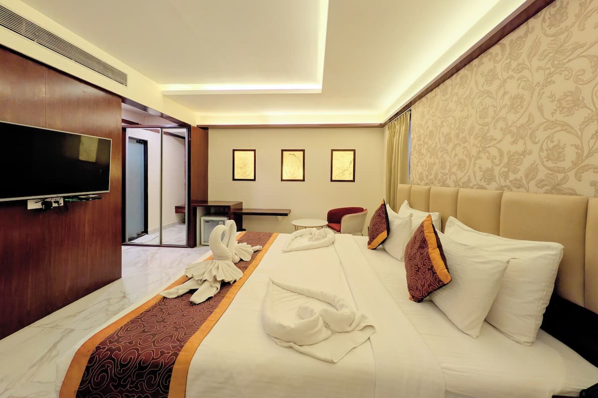 A hotel room with a bed, a TV, a desk, and a chair.