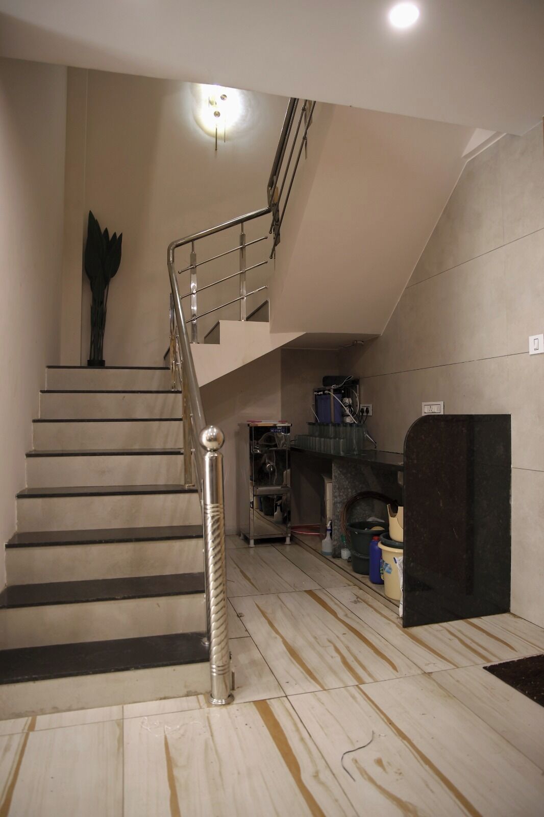A staircase with a metal handrail, a wall-mounted sculpture, and a fireplace with storage items.