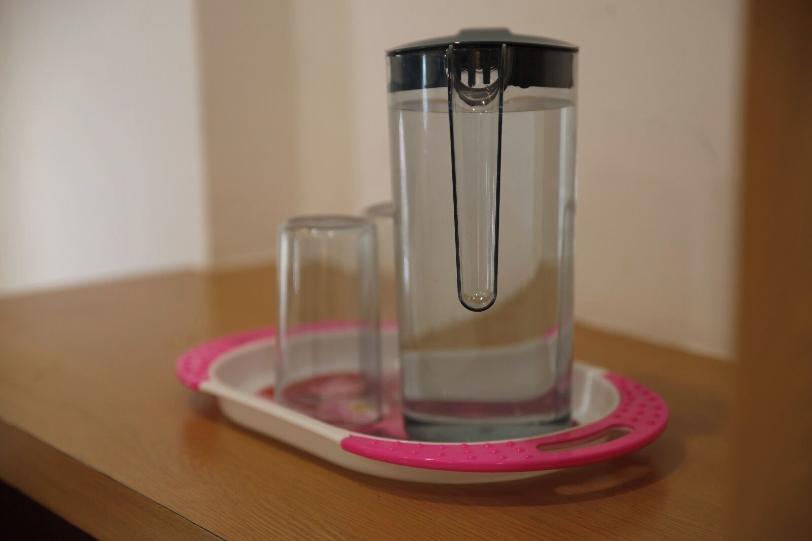 A water filtration pitcher on a pink tray.