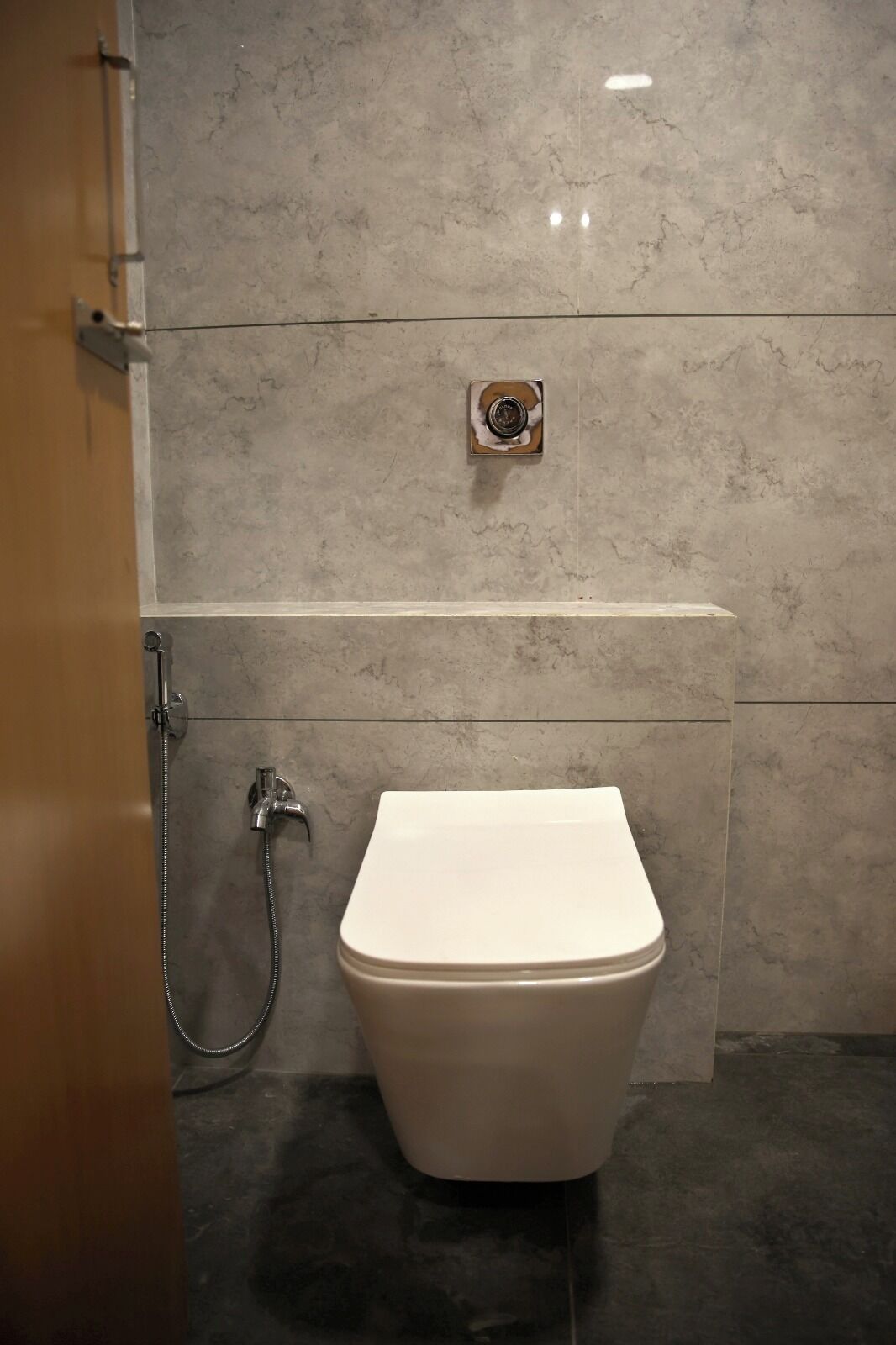 A modern bathroom with a toilet, a shower, and a wall-mounted faucet.