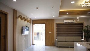 Un intérieur moderne avec un mur d’accent en bois, un téléviseur à écran plat, un canapé beige et un comptoir d’accueil.