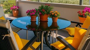 Un espacio de estar techado al aire libre con una mesa redonda, sillas y plantas en macetas.