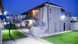 Una casa moderna de dos pisos con balcón, escalera y césped bien cuidado.
