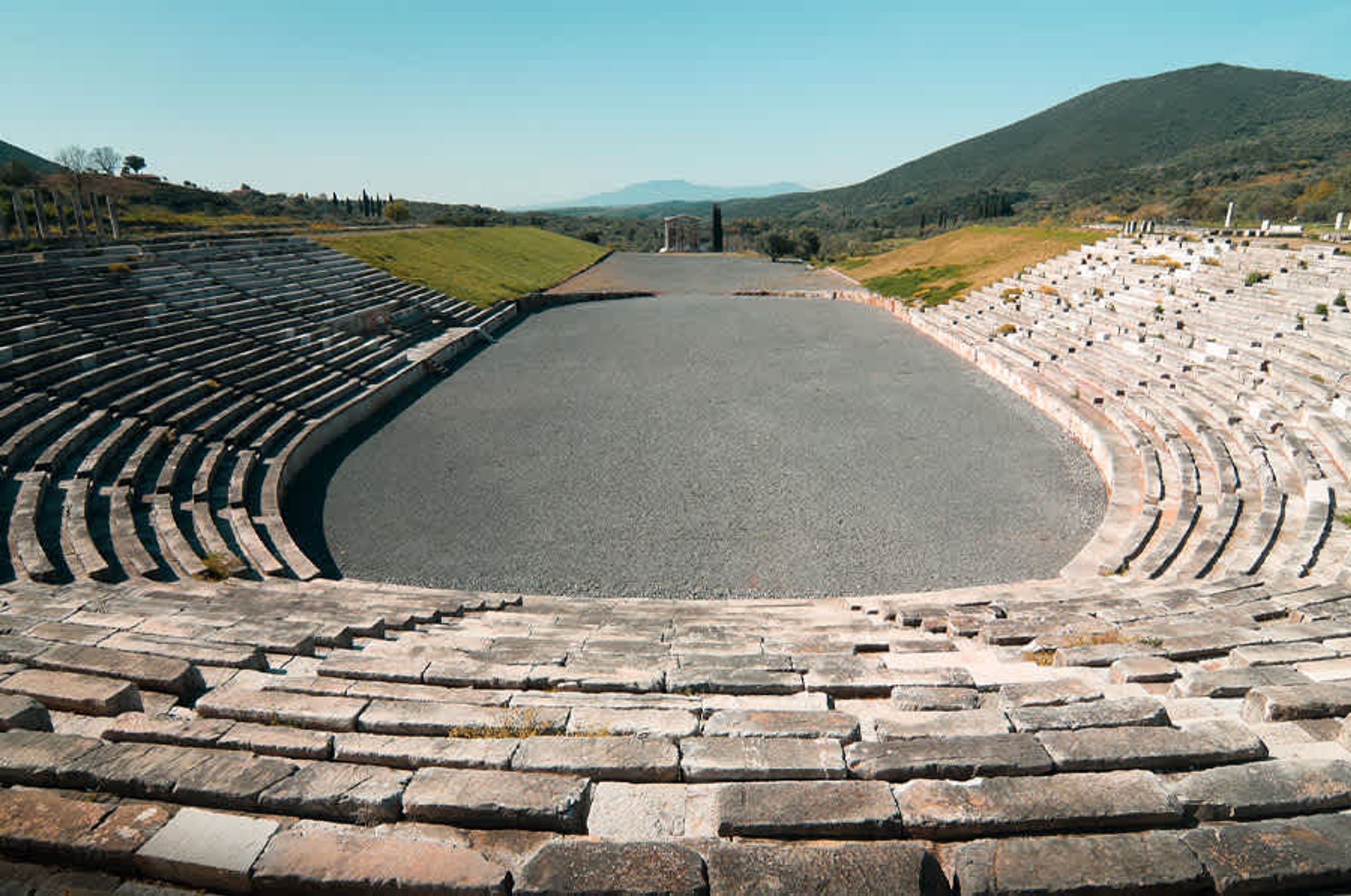 Un anfiteatro al aire libre con asientos escalonados y un escenario central.