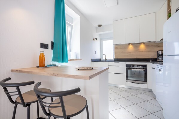 A modern kitchen with white cabinets, a wooden countertop, and a built-in oven.