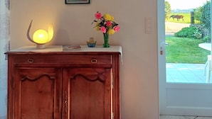 A wooden cabinet with a lamp, a framed picture, and a vase with flowers on a table.