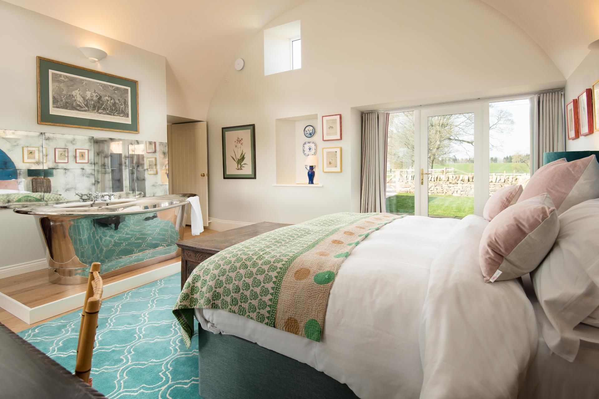 Een ruime slaapkamer met een groot bed, een kaptafel met spiegel, en uitzicht op de omgeving door een groot raam.