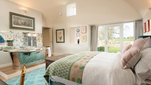 A spacious bedroom with a large bed, a vanity with a mirror, and a view of the outdoors through a large window. - Lakeside Cottage, Emily in Capheaton, Northumberland - sleeping 2 guests in one bedroom (Capheaton)