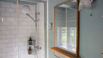 Un baño con ducha de vidrio, un estante de madera y un espejo montado en la pared.