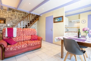 A cozy living area with a sofa, a dining table, and a kitchen in the background.