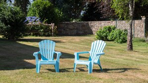 Two Adirondack chairs in a grassy outdoor area with a stone wall and trees in the background. - Gîte Glycine, Kerantum: Shared Garden and Wi-Fi in Mahalon (Mahalon)