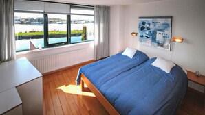 A hotel room with two beds, a view of a body of water, and a poster on the wall. - Stunning home in Lemmer with WiFi (Lemmer)