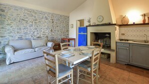 A cozy living room with a stone wall, a blue refrigerator, a fireplace, and a kitchen area with cabinets and a sink.
