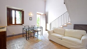 A spacious living area with a glass dining table, a white sofa, and a staircase leading to an upper level. - Amazing apartment in San Vito in Monte (San Vito in Monte)