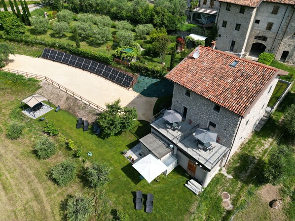 Eine Übersichtsansicht eines Anwesens mit einem Steinhaus, einem überdachten Außenbereich und Solaranlagen.