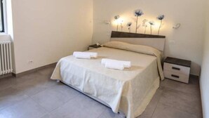 Un dormitorio con cama, mesitas de noche, un radiador y una pared con luces decorativas.