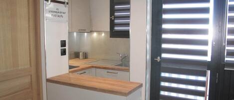A modern kitchen with a wooden countertop, a sink, and a stainless steel range hood.