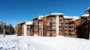 En flerlagsbygning i træ med balkoner, omgivet af sne.