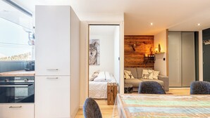 Et moderne køkken med hvide skabe, indbygget ovn samt spiseområde med bord og stole.