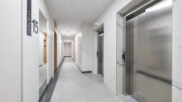 A modern hallway with a marble floor, a number '15' sign, and a stationary elevator.