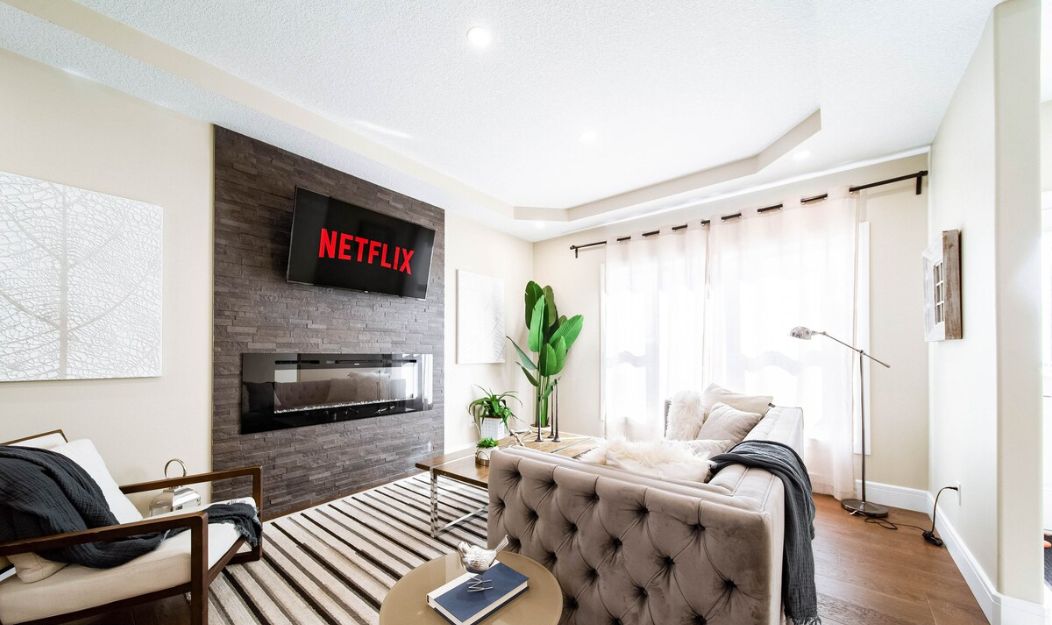 A modern living room with a fireplace, a sofa, a coffee table, and a large plant.