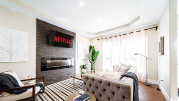 A modern living room with a fireplace, a sofa, a coffee table, and a large plant.