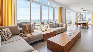 Un salon moderne avec un grand canapé, une table basse et un coin repas comprenant une table et des chaises.