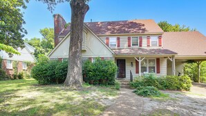 A two-story house with a front porch, a chimney, and a well-maintained lawn. - 4 BD Family Home w/ Yard & Bbq! in Memphis (Memphis)