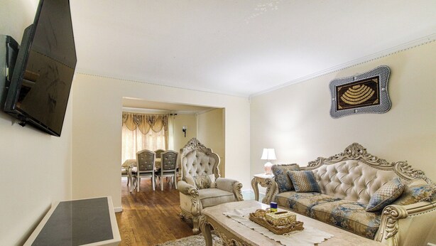 A living room with a sofa, armchair, and coffee table. There is a television mounted on the wall and a door leading to another room. - 4 BD Family Home w/ Yard & Bbq! in Memphis (Memphis)