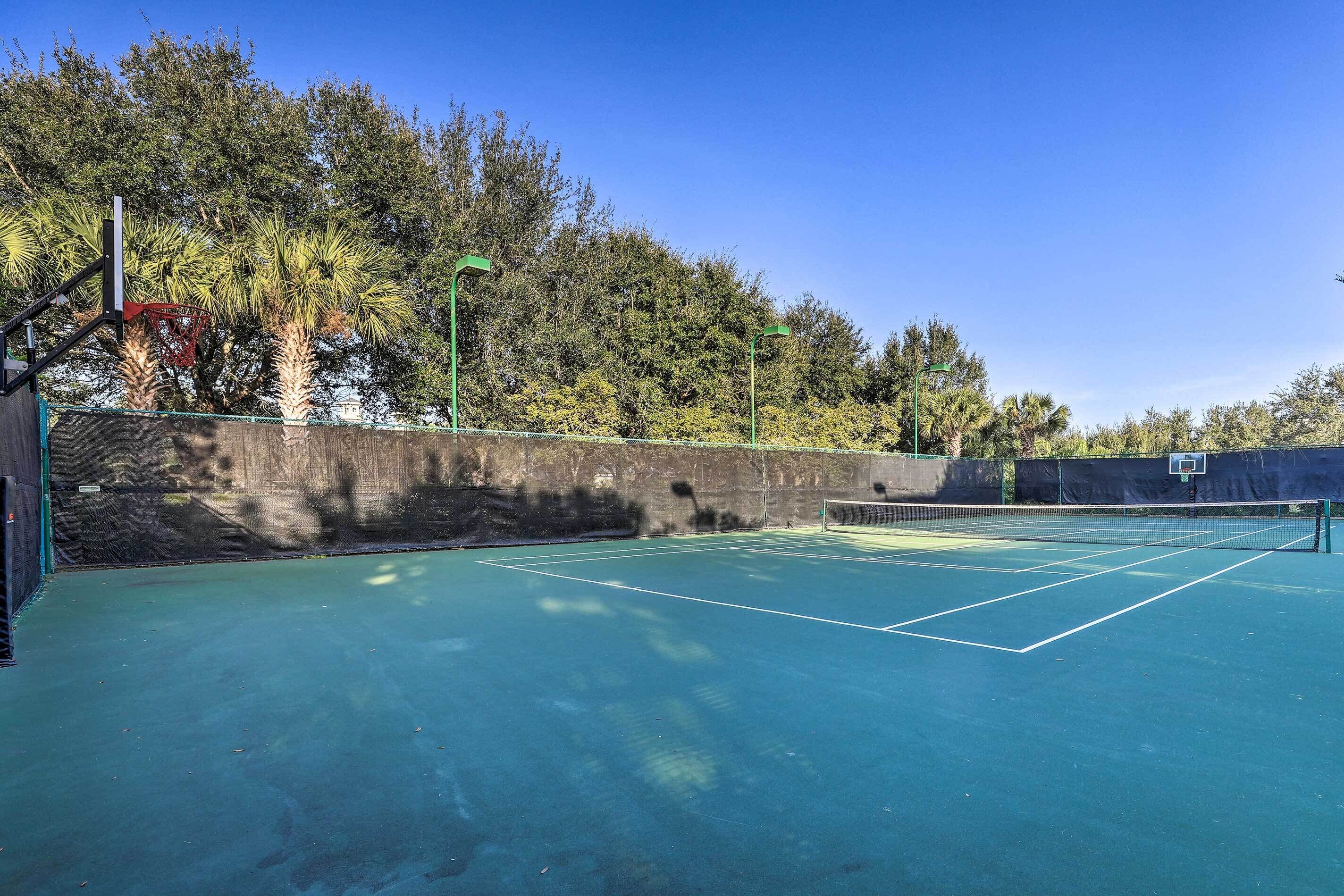 Una cancha de tenis con una red, rodeada de árboles y una pared.