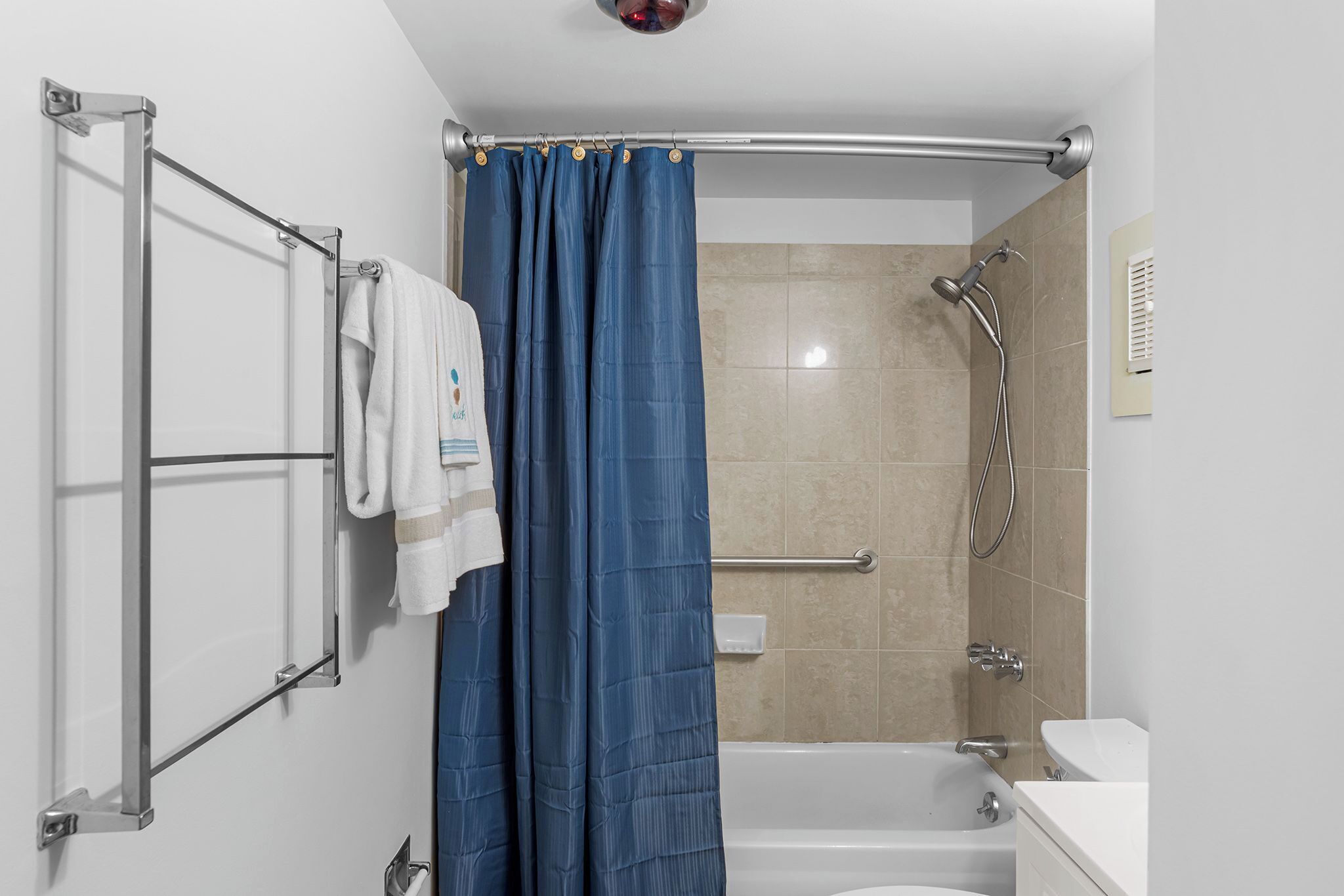 A bathroom with a bathtub, shower, and a towel rack with towels.