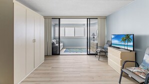 Una sala de estar moderna con un televisor grande, un sofá, una mesa de centro y vistas a la playa a través de una puerta corrediza.