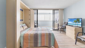 Un dormitorio con cama, televisión, escritorio y silla.