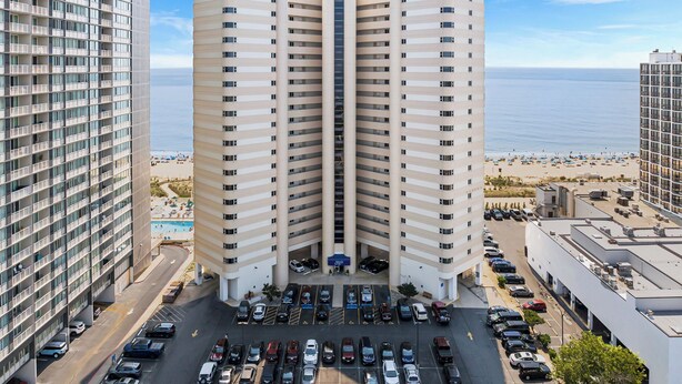 Un hotel de gran altura con un atrium central, estacionamiento y vista a la playa.