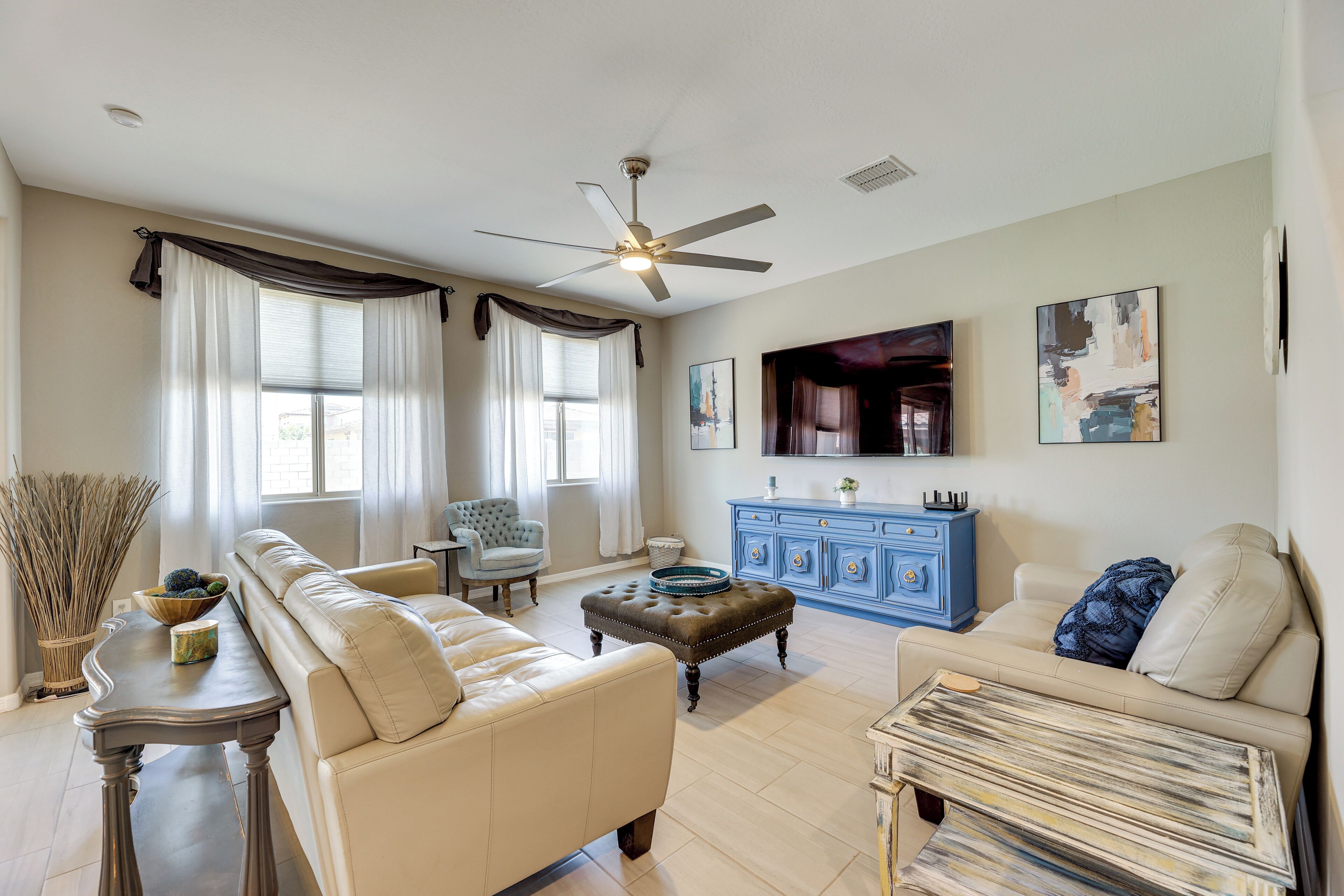 A living room with a beige sofa, a blue cabinet, a television, and artwork on the wall.