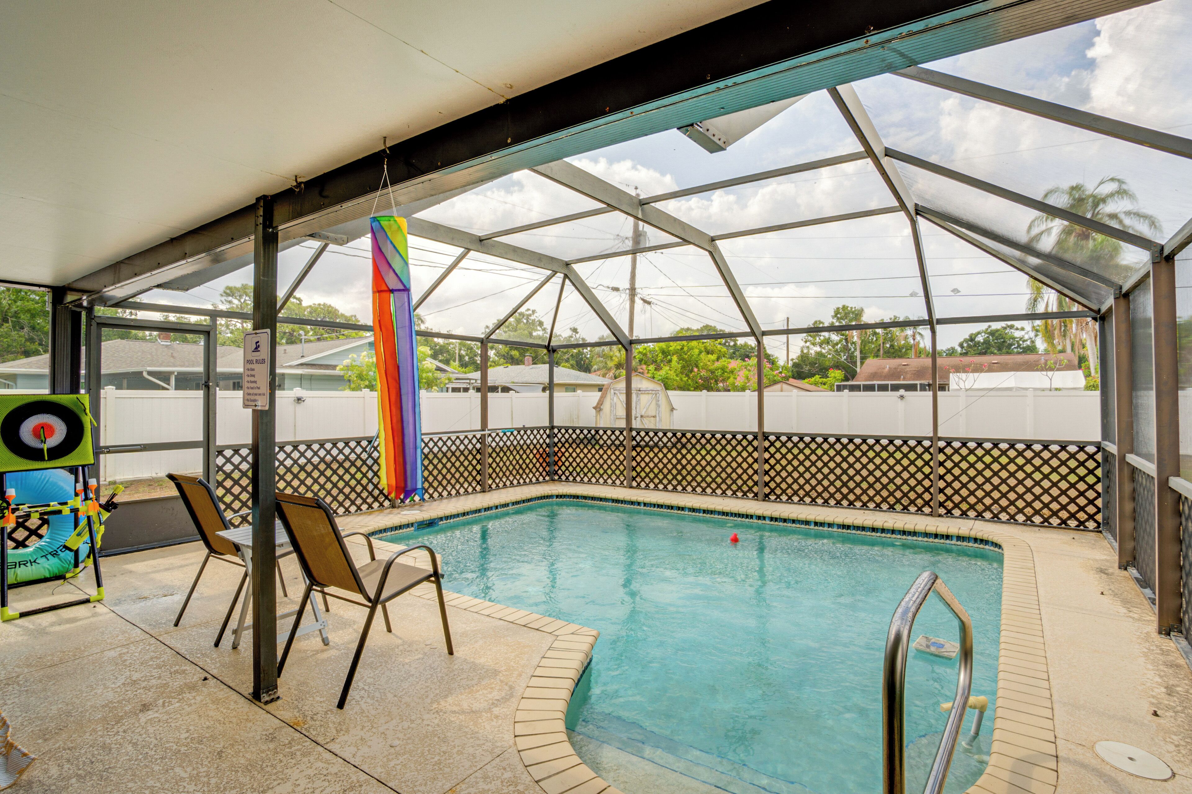 A covered swimming pool with chairs and a colorful water toy.