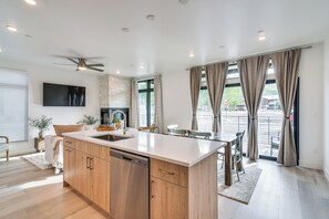 Een moderne keuken met een centraal eiland, houten kastjes en een inbouwvaatwasser.