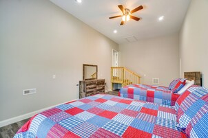 A bedroom with a large bed, a ceiling fan, and a staircase leading to an upper level.